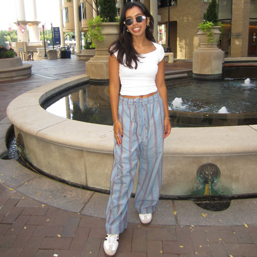 Woman standing in front of a fountain on a city street