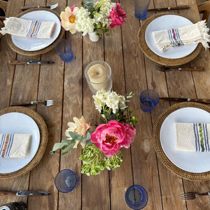 Dining table set with plates, flowers, and glasses on a wooden surface