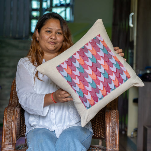 Woman holding a colorful patterned pillow in an indoor setting